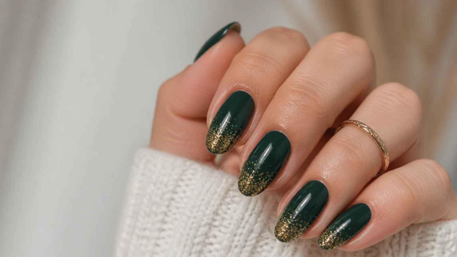 Deep green nails with fine gold glitter fading up from the tips