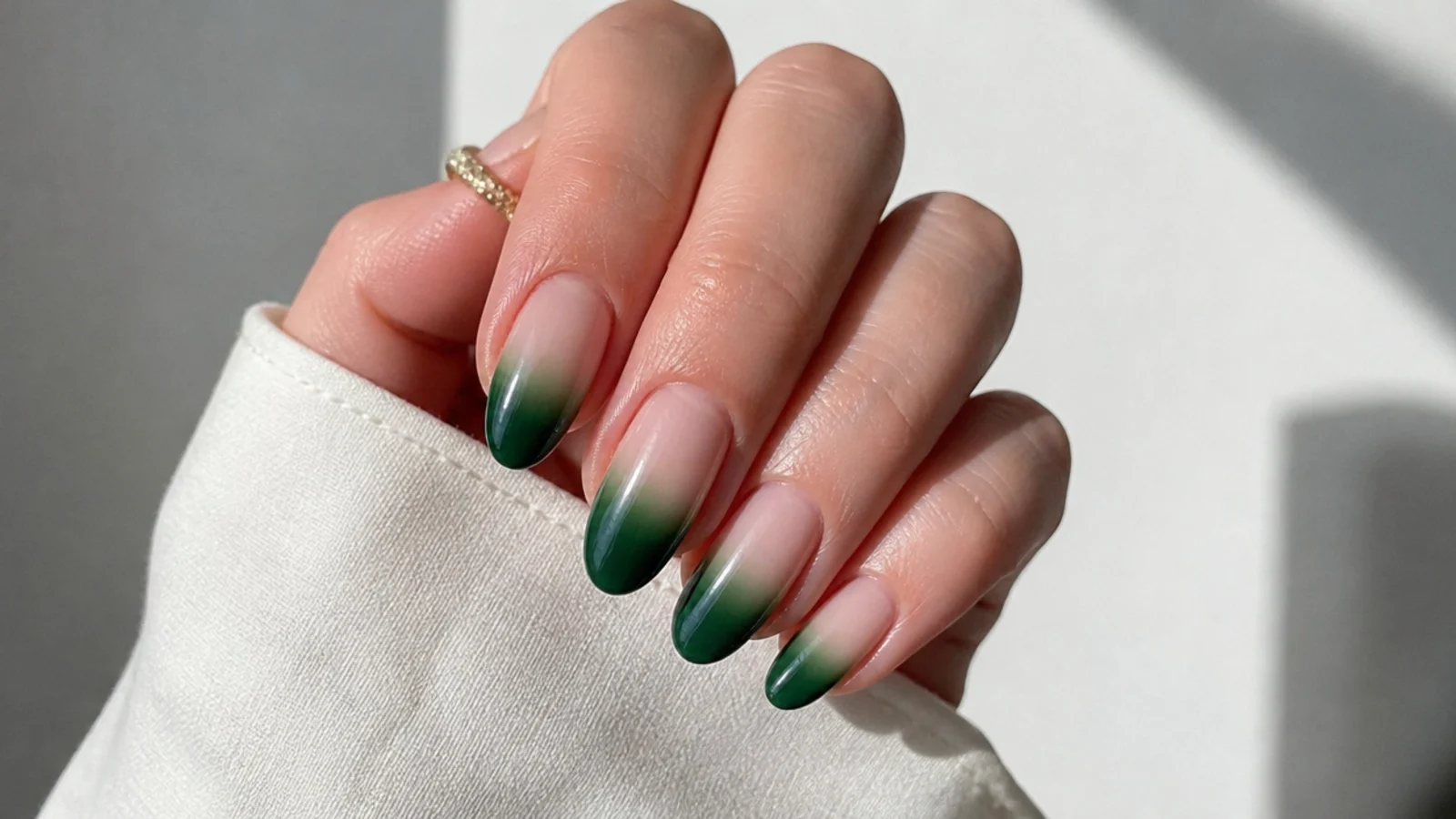 Nails fading from nude at the base to deep emerald green tips