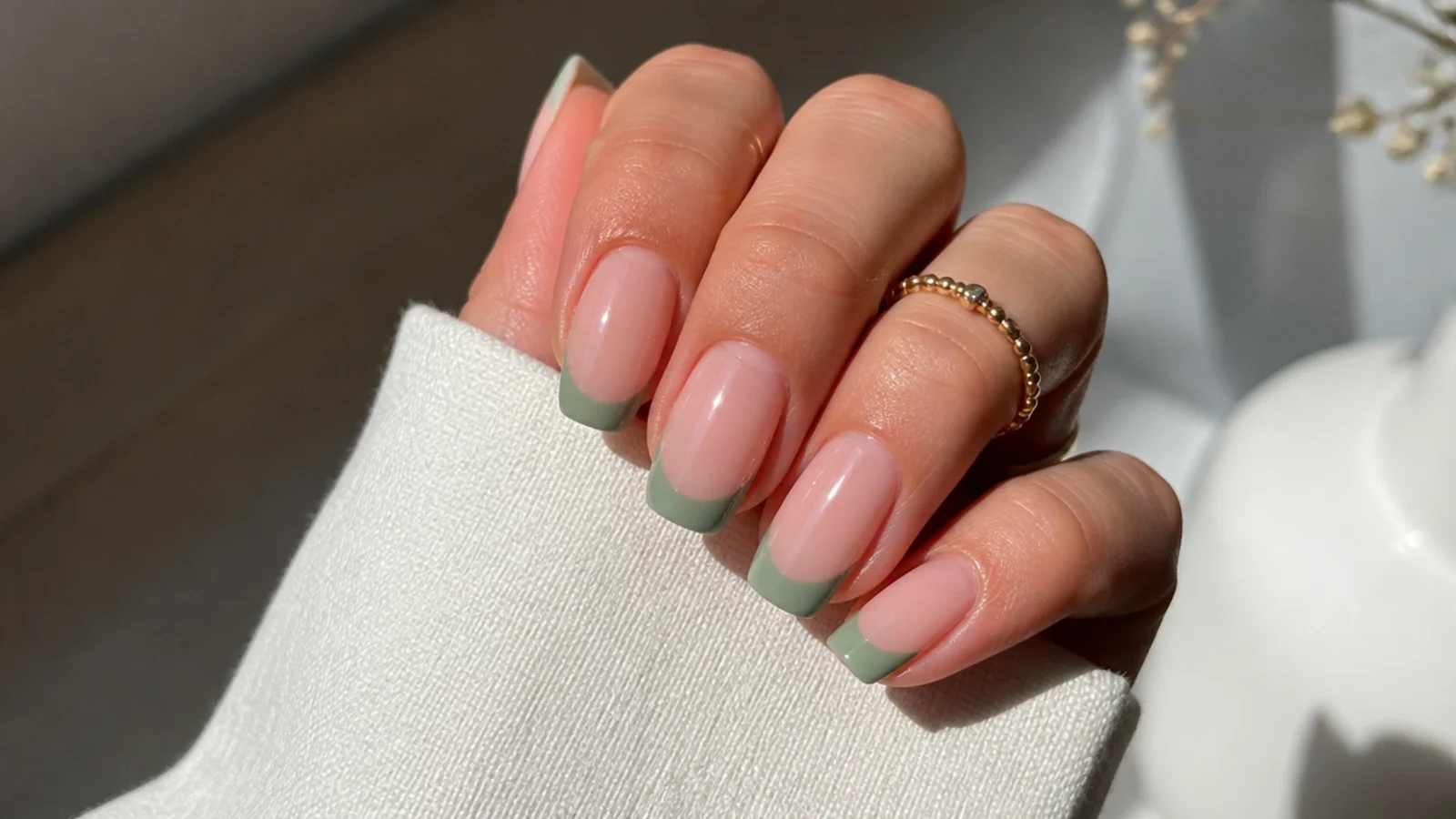 Soft nude nails with muted sage-green french tips