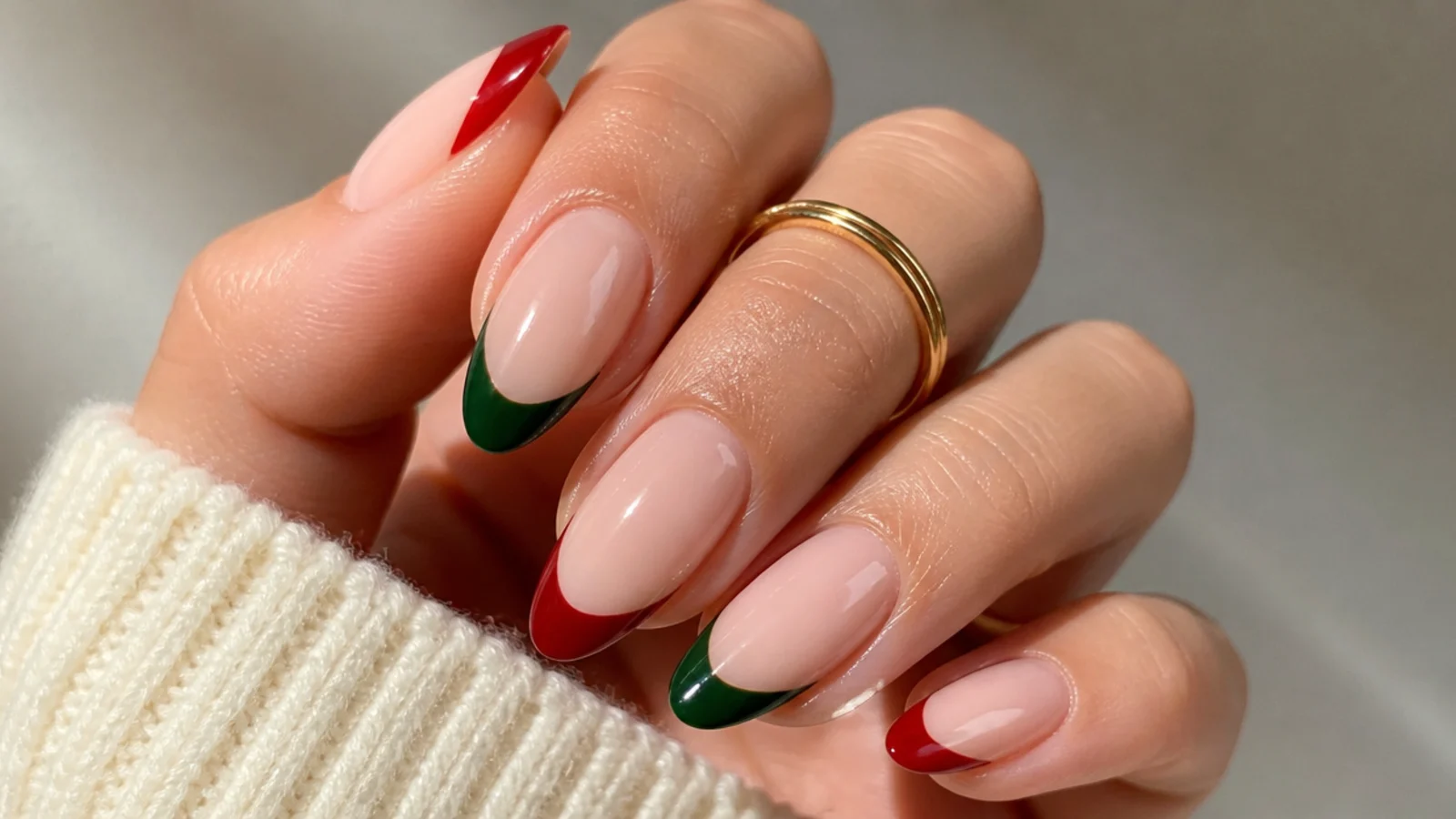 Almond December nails with alternating red and green French tips on nude