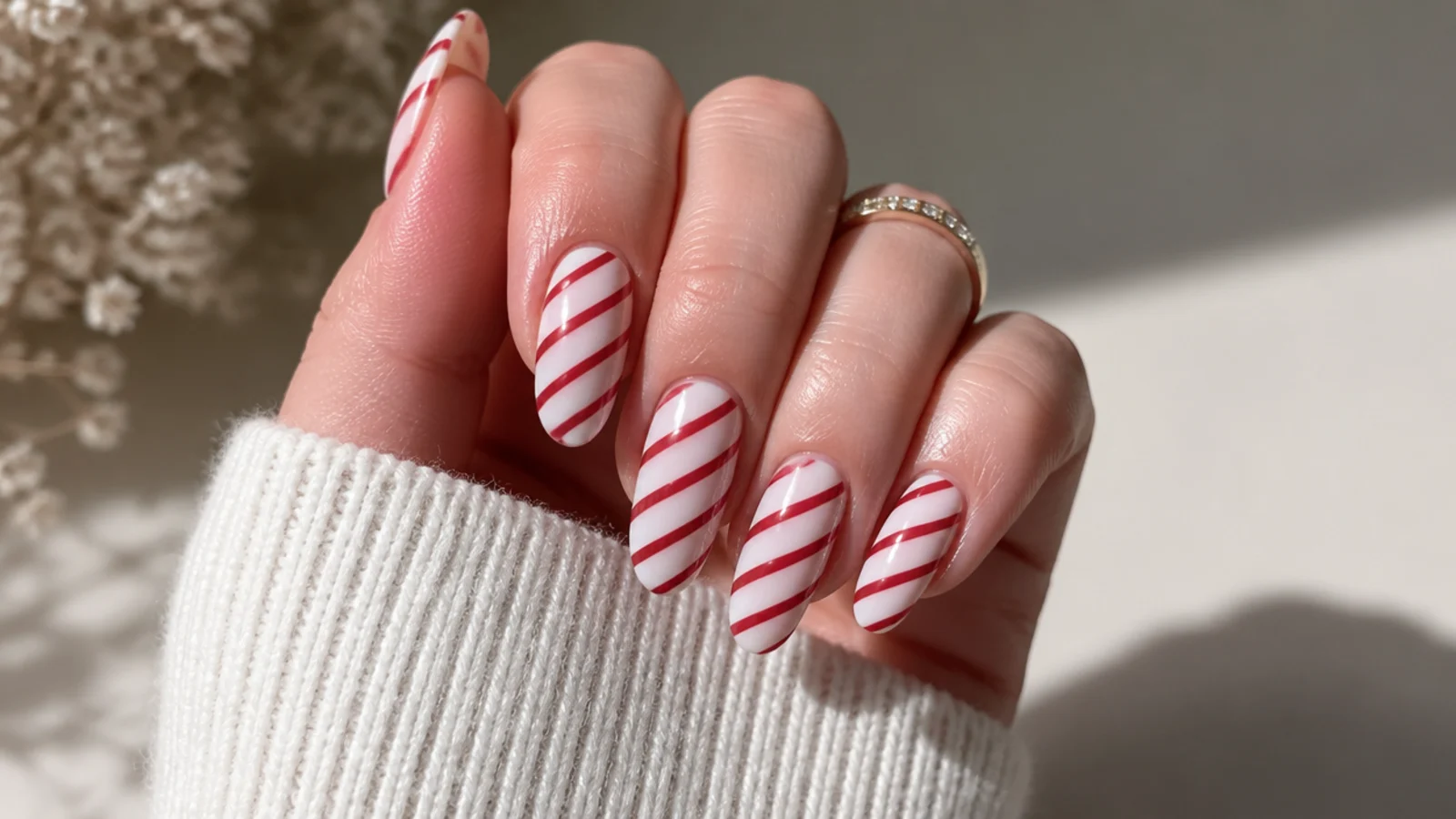 White almond December nails with diagonal red candy cane stripes