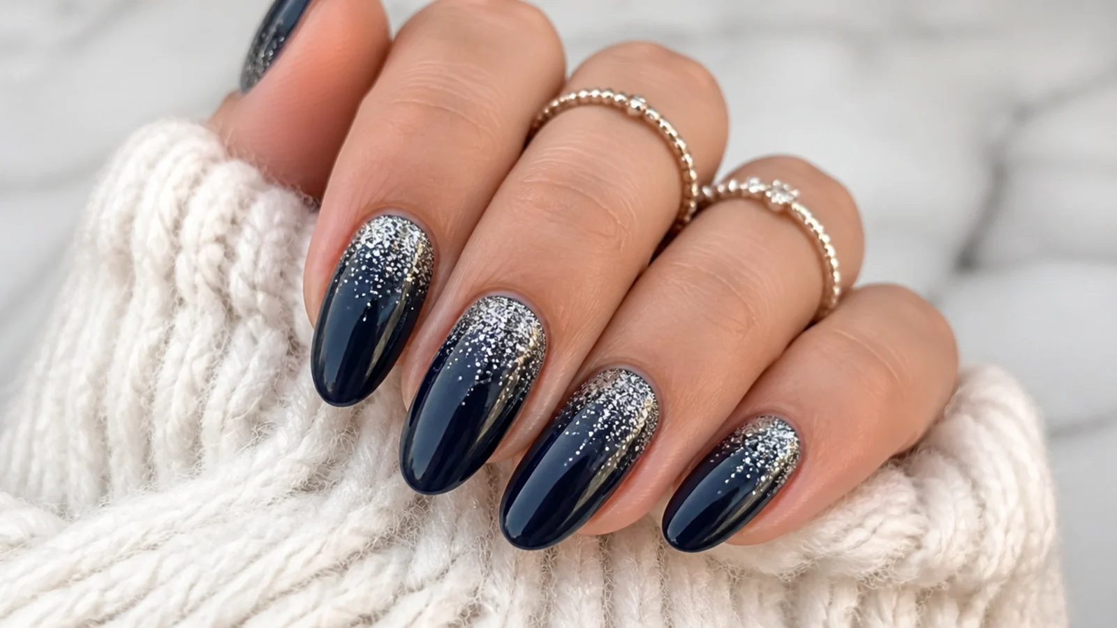 Deep navy December nails with silver glitter fading from the cuticle