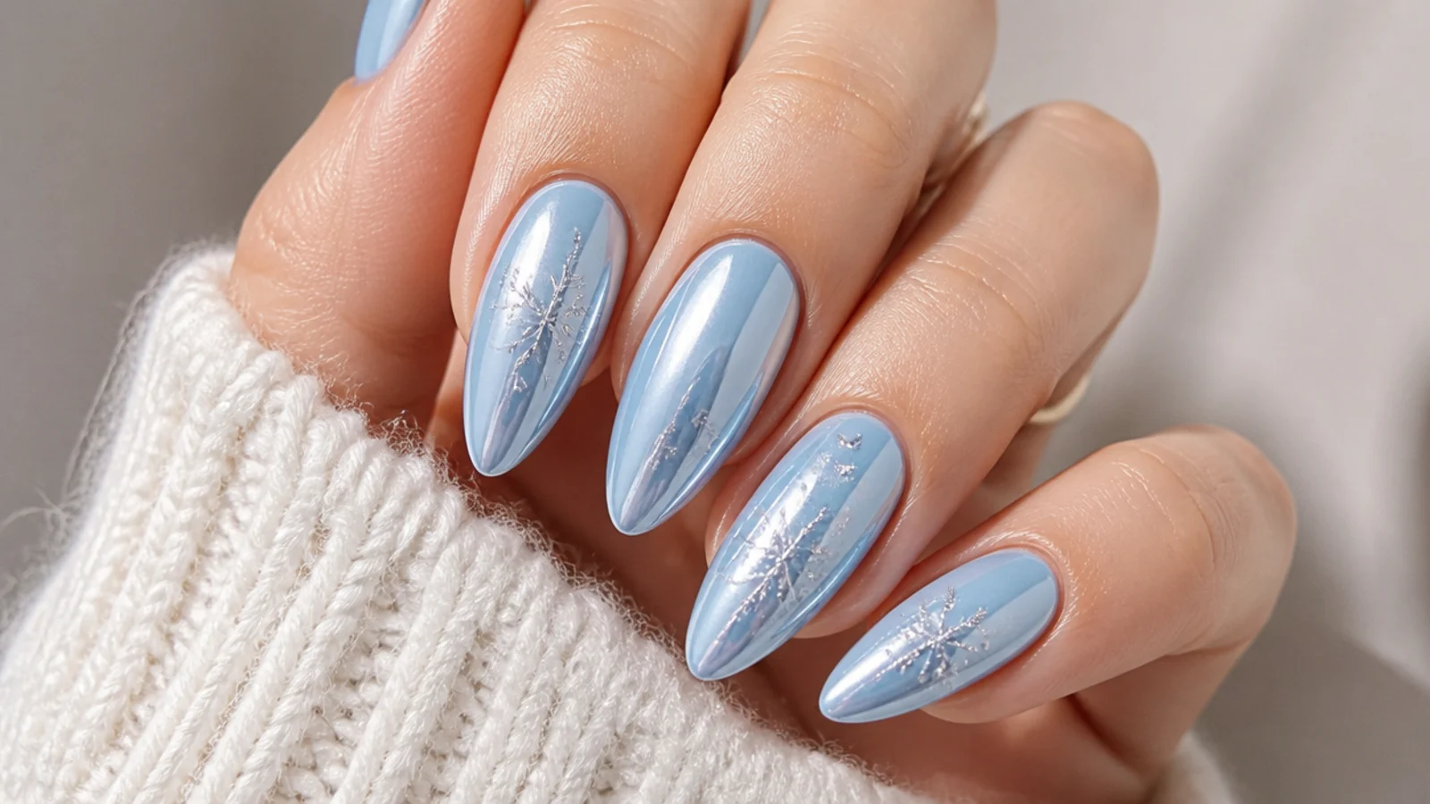 Icy blue chrome December nails with silver snowflake accents on almond shape