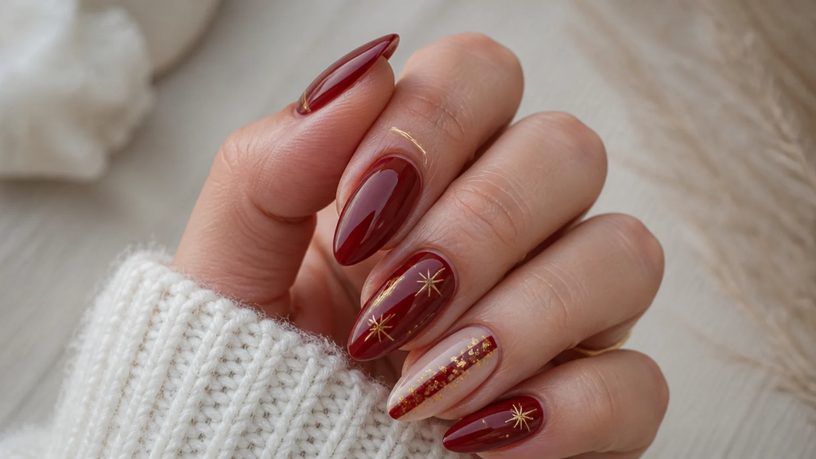 Rich red December nails with gold accents and a jewel-toned finish