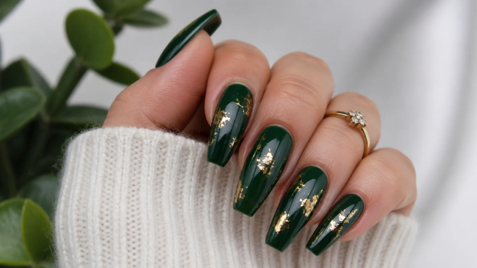 Deep forest green December nails with gold foil flecks on coffin tips