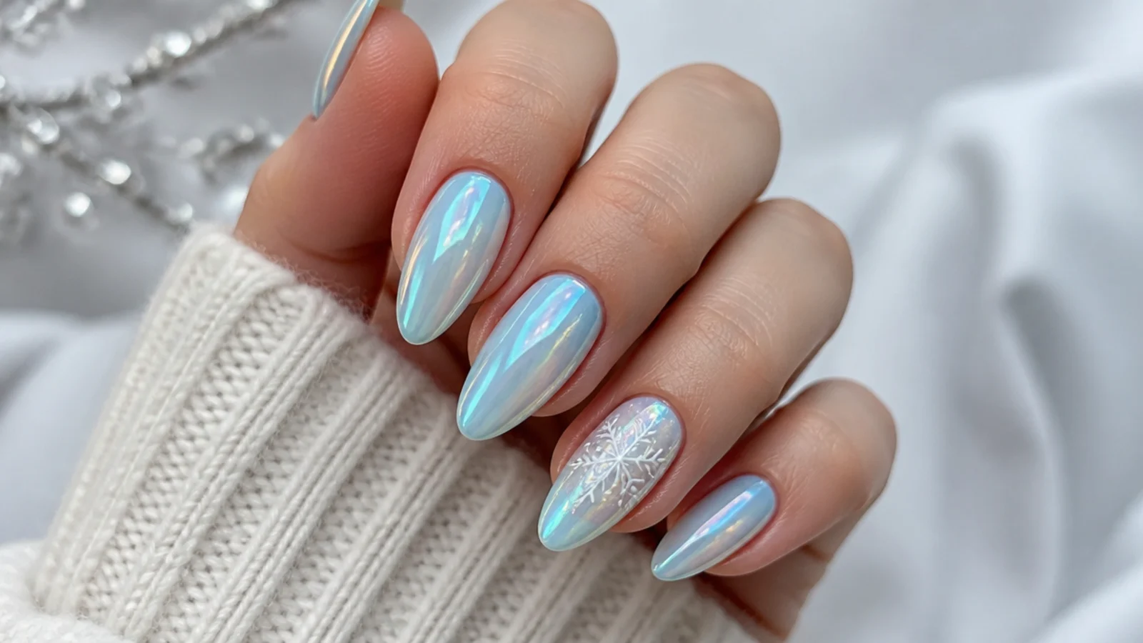 Icy blue chrome December nails with white snowflake accent on almond tips