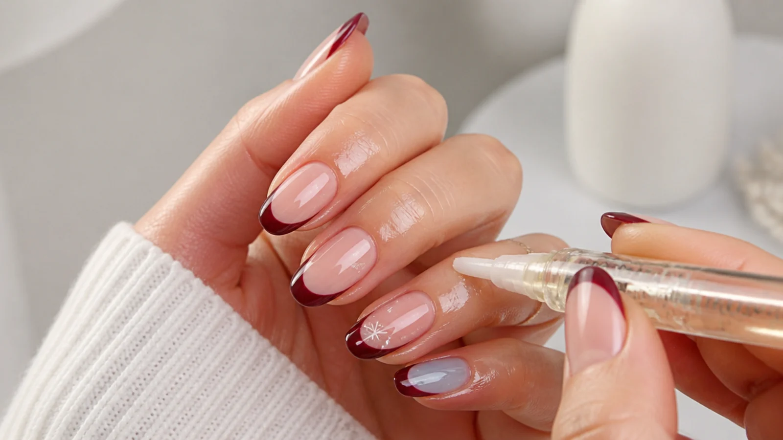 Cuticle oil being massaged around finished glossy December nails