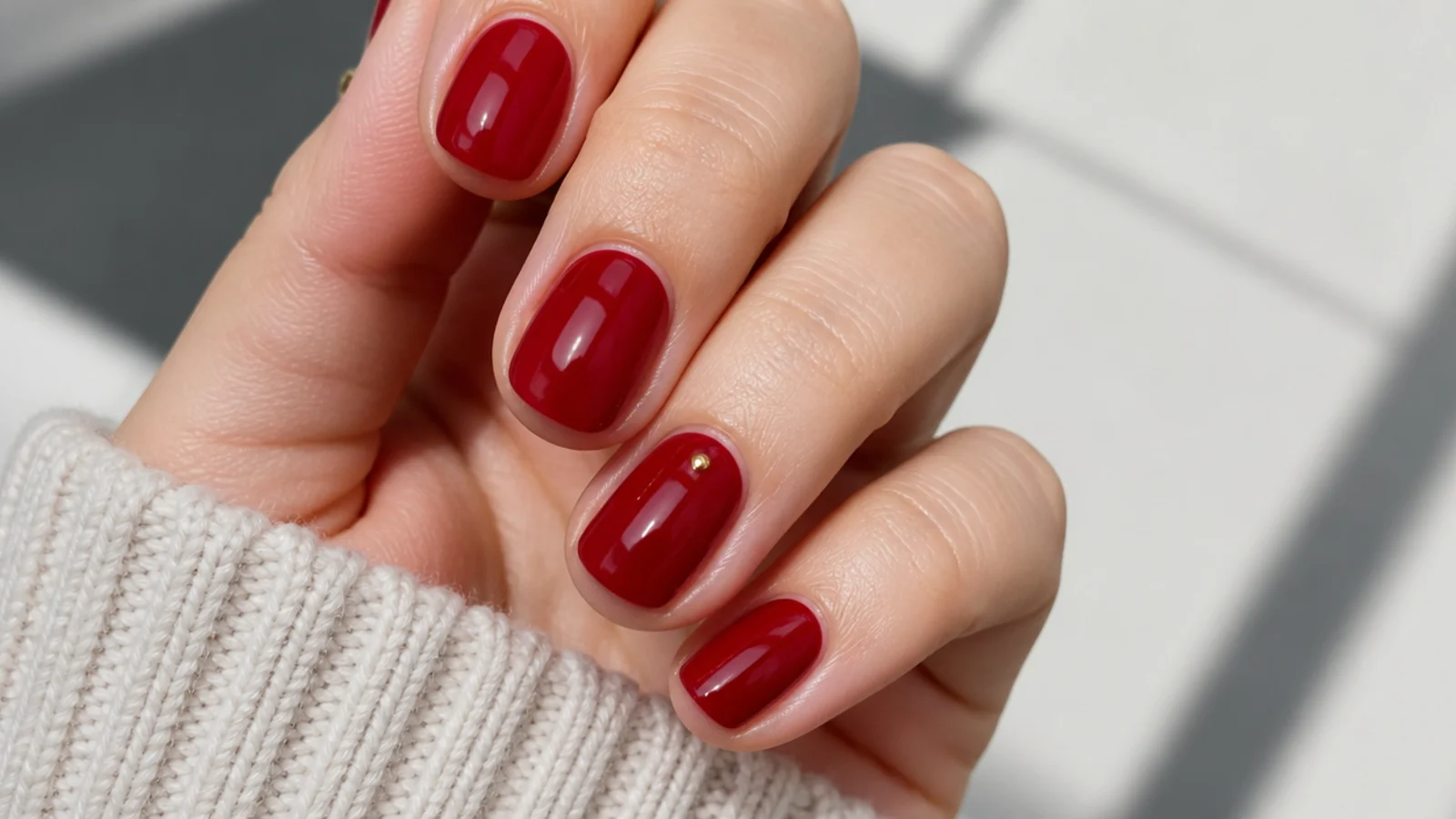 Short natural glossy red December nails with one gold dot accent