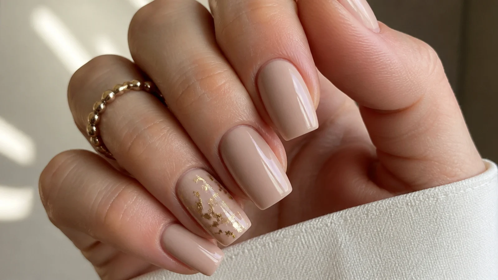 Nude square nails with torn gold-foil flakes on one accent nail