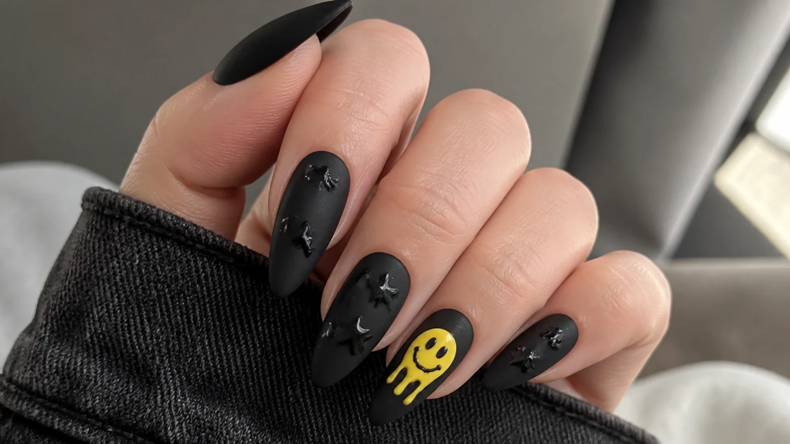 Black emo nails with a melting yellow smiley face on an accent nail