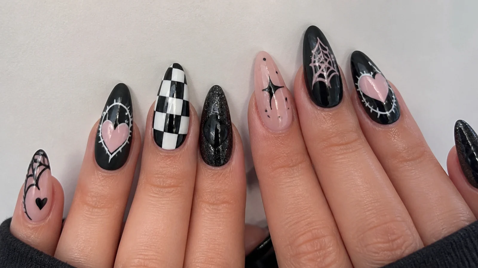 Black emo nails with checkerboard, hearts and spiderweb motifs side by side
