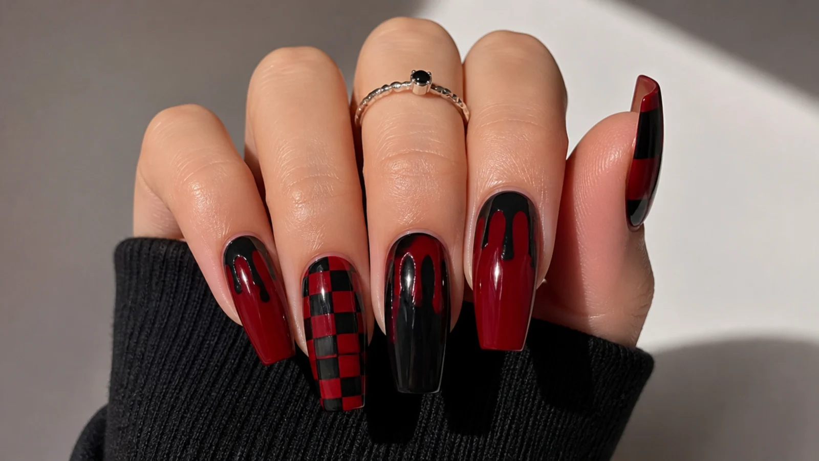 Deep red nails with black checkerboard and dripping paint motif on coffin shape