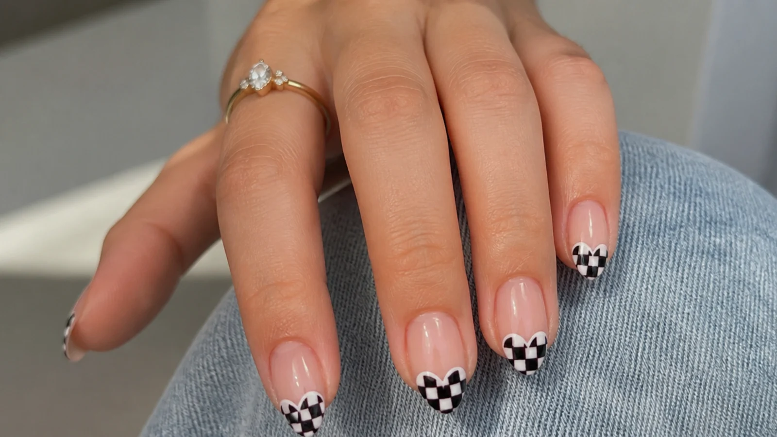 Nude nails with black-and-white checkerboard tips shaped into a heart