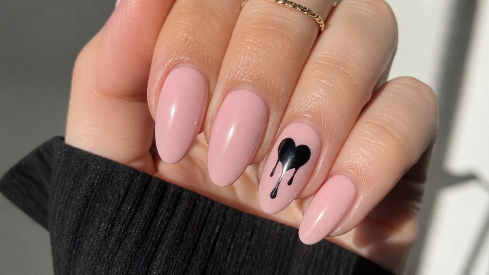 Pink nails with a black heart that drips down the nail on the accent finger