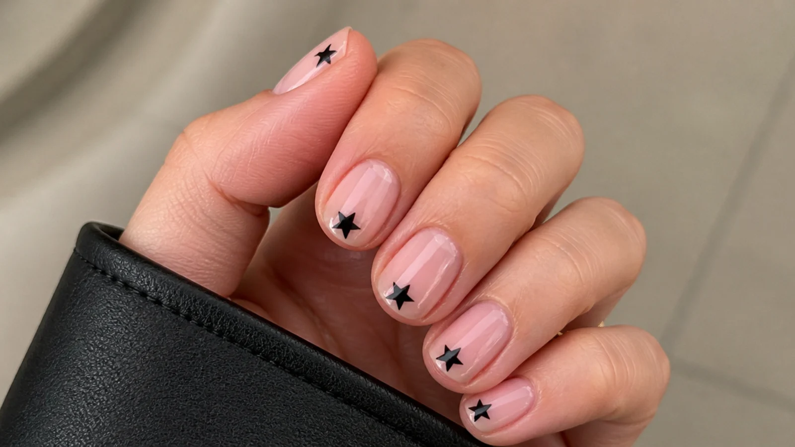 Short round pink nails with small black stars at the tips for a subtle emo look