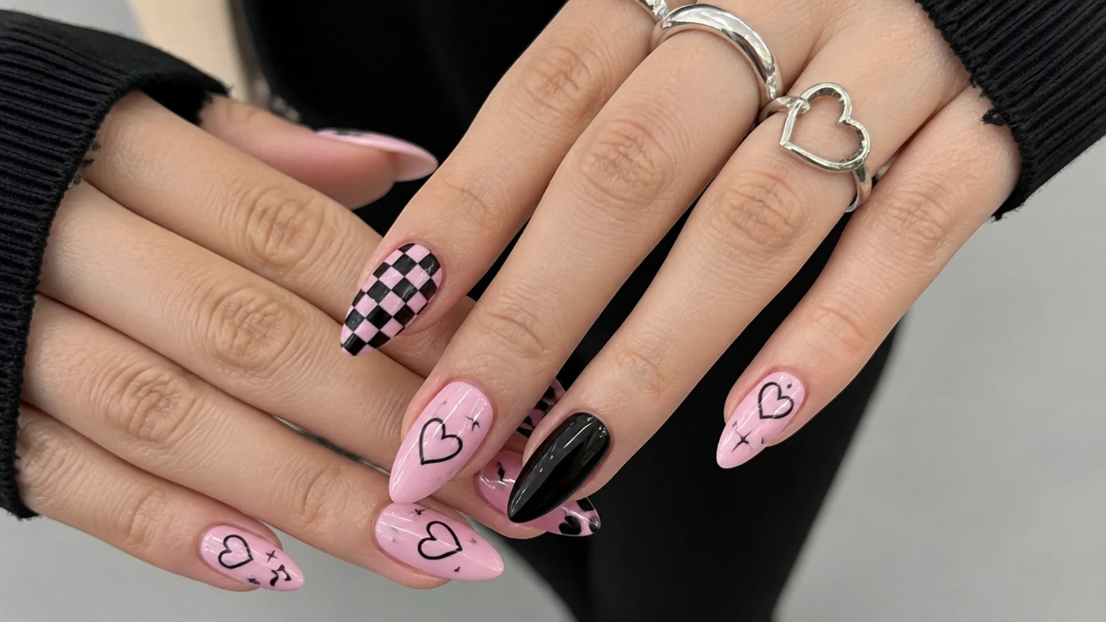 Cute emo nails in soft pink and black with hearts and checkerboard on almond shape