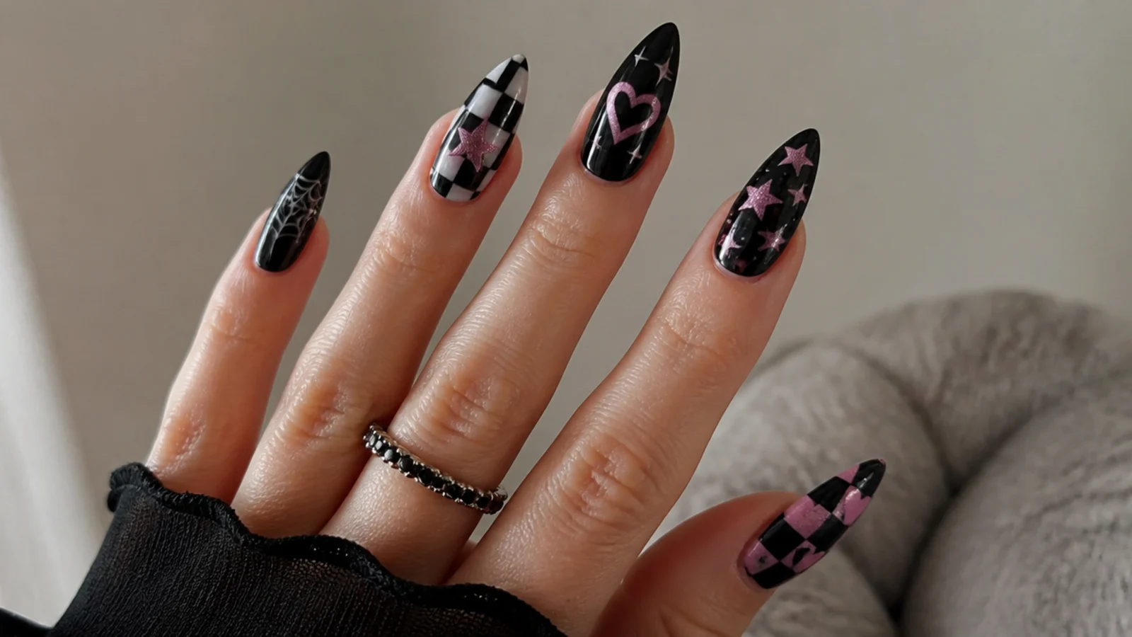 Black-based nails with checkerboard, hearts, stars and spiderweb emo motifs