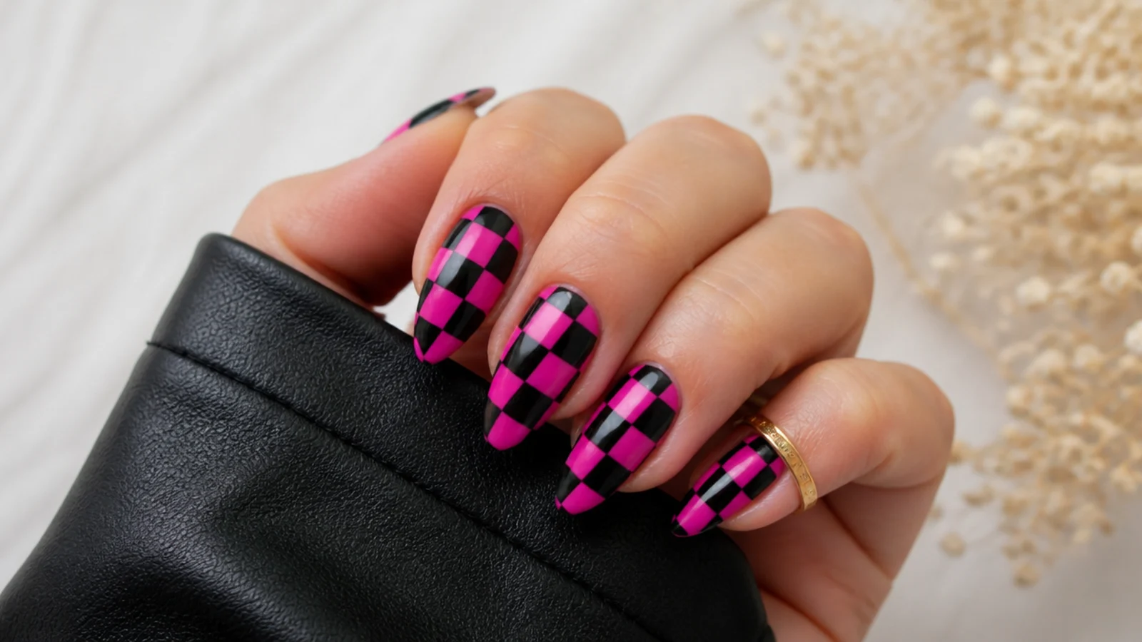 Hot pink and black checkerboard acrylic nails on an almond shape