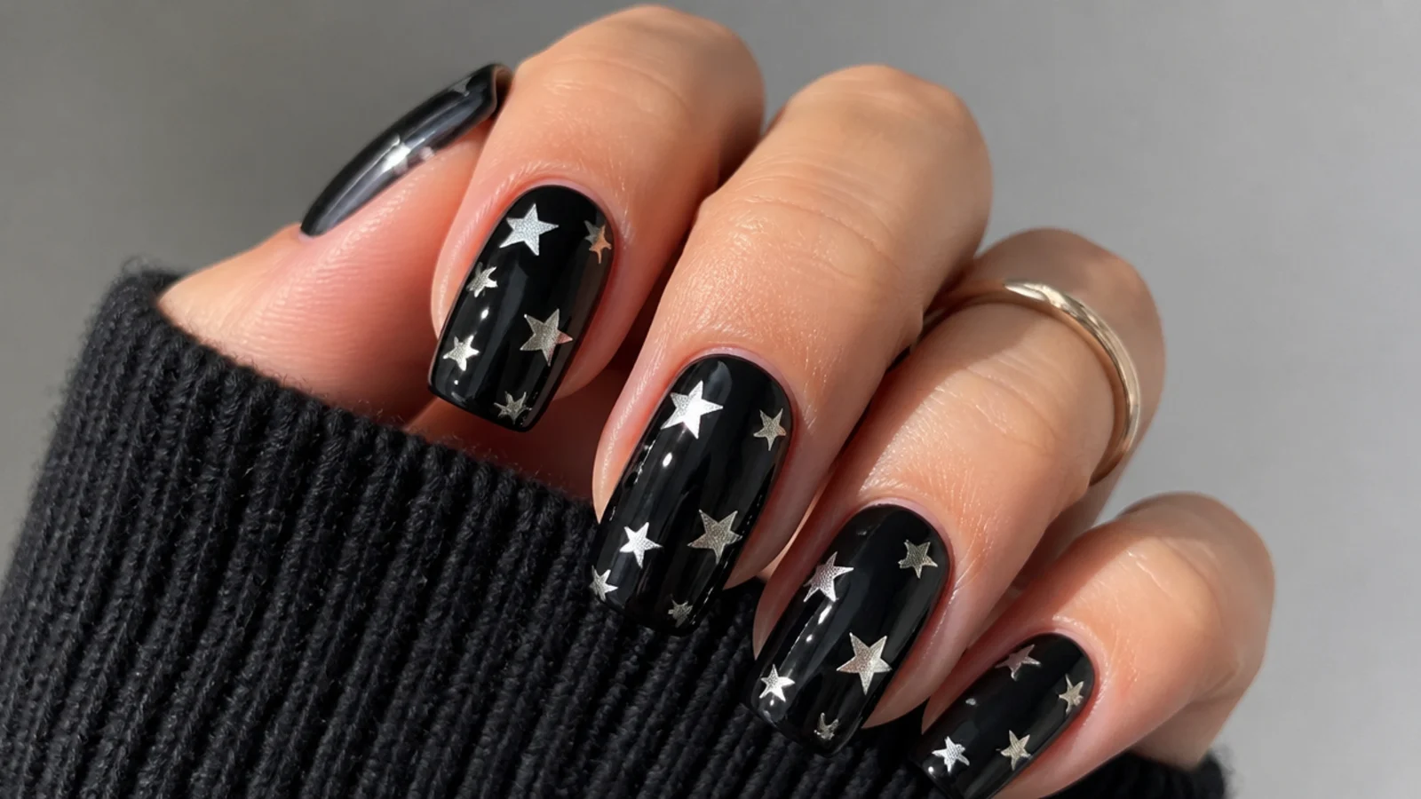 Silver and white five-point stars scattered over black acrylic nails