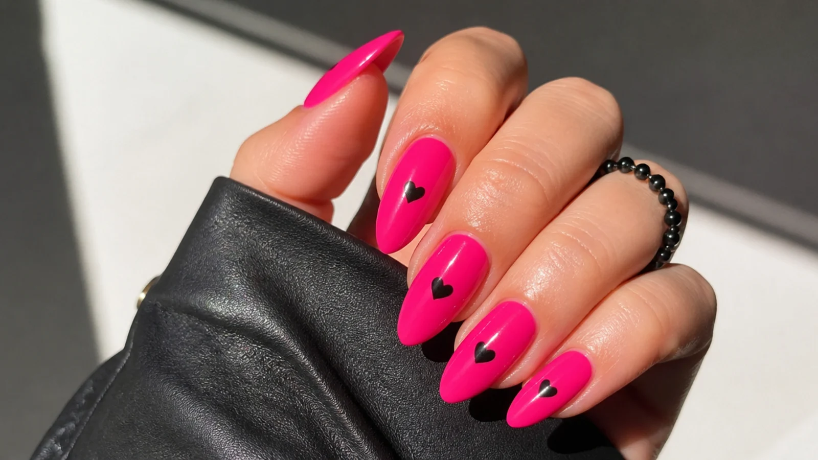 Hot pink nails with small black heart accents, emo baddie style