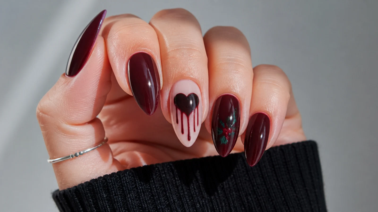 Deep oxblood emo nails with a black bleeding heart and tiny holly sprig accent