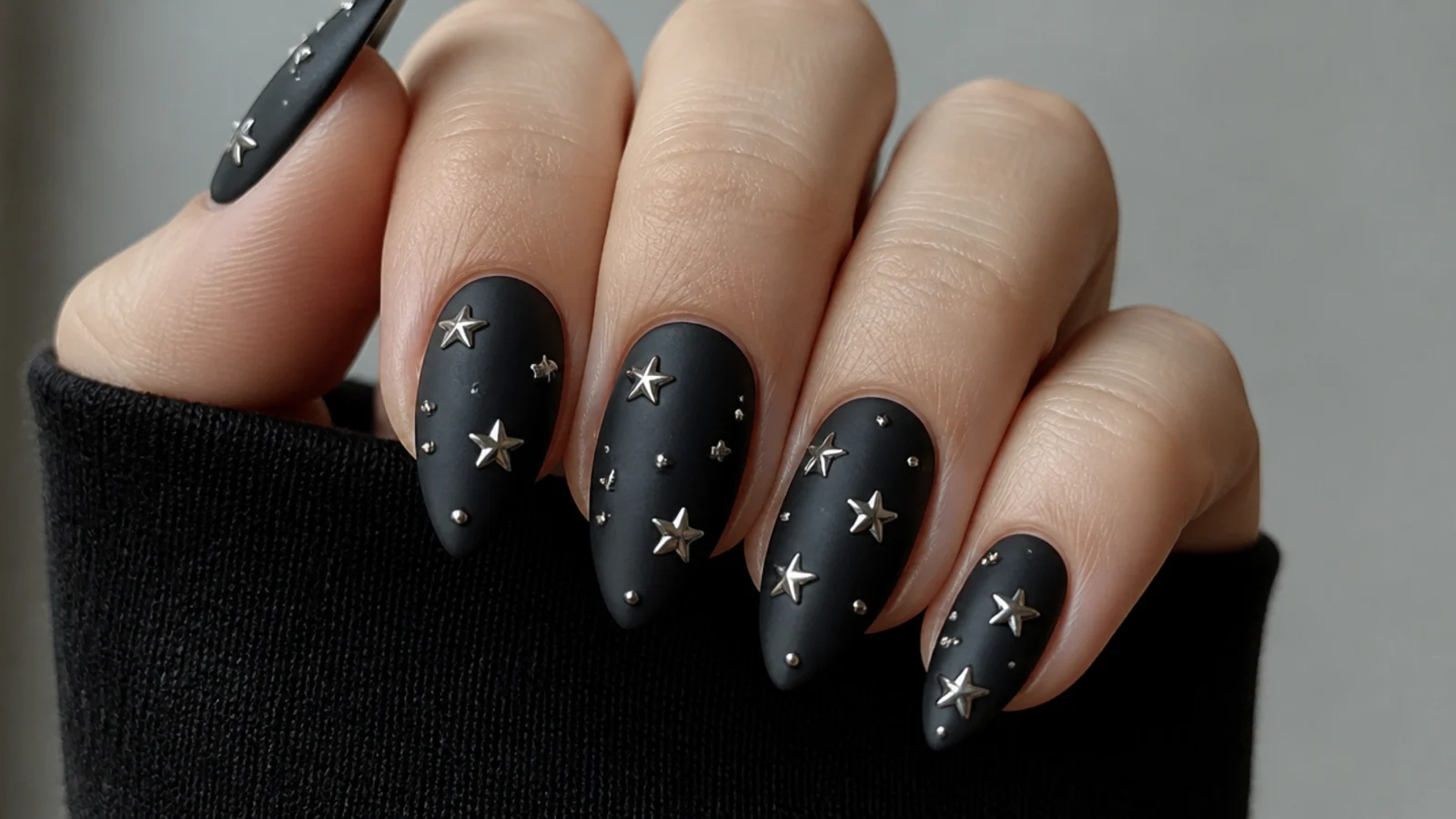 Matte black emo nails scattered with tiny silver five-point stars and studs