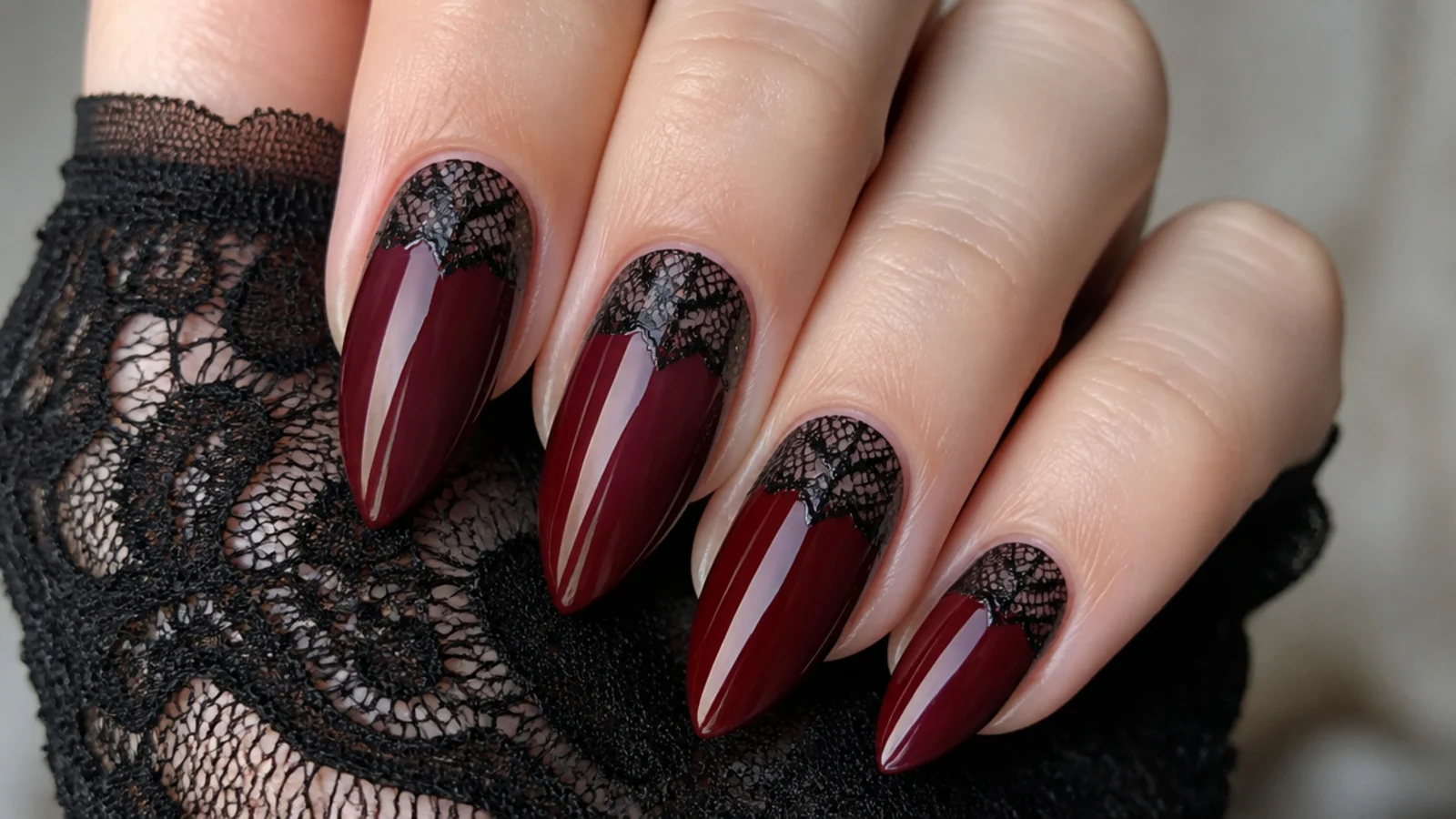 Deep red emo nails with delicate black lace pattern near the cuticle like a Victorian cuff