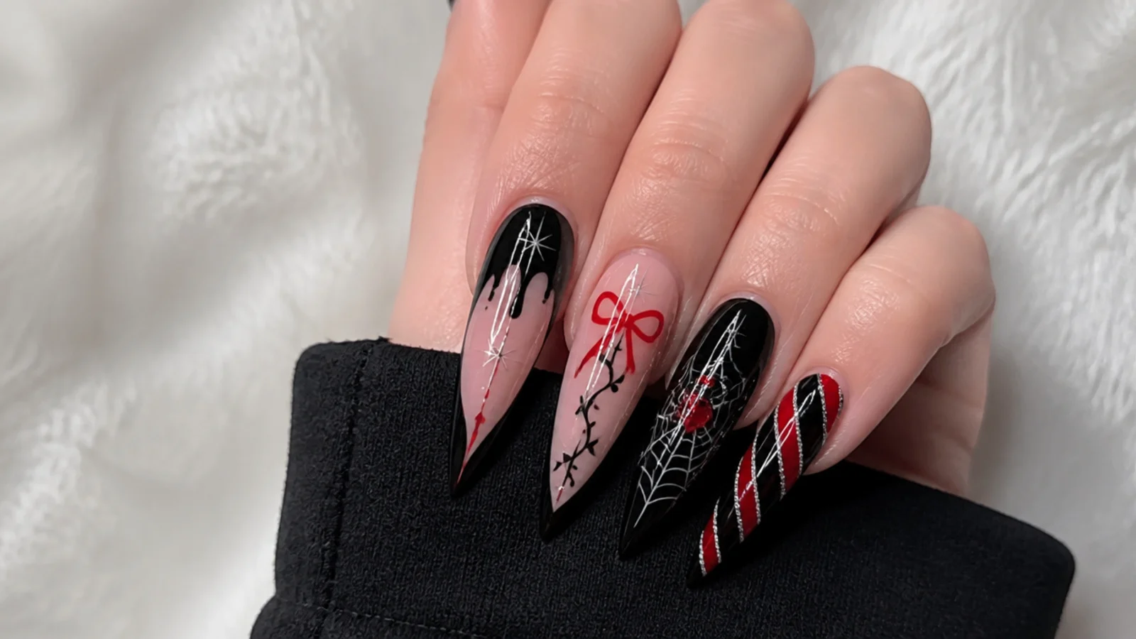 Long black stiletto emo Christmas nails mixing drips, webs, hearts and red accents across the hand
