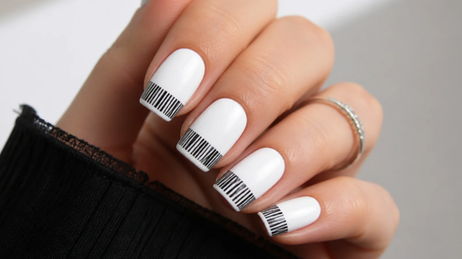 White emo nails with a black barcode graphic across the tips