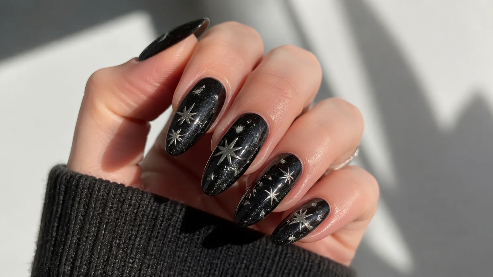 Deep black glitter emo nails with silver stars and a galaxy shimmer