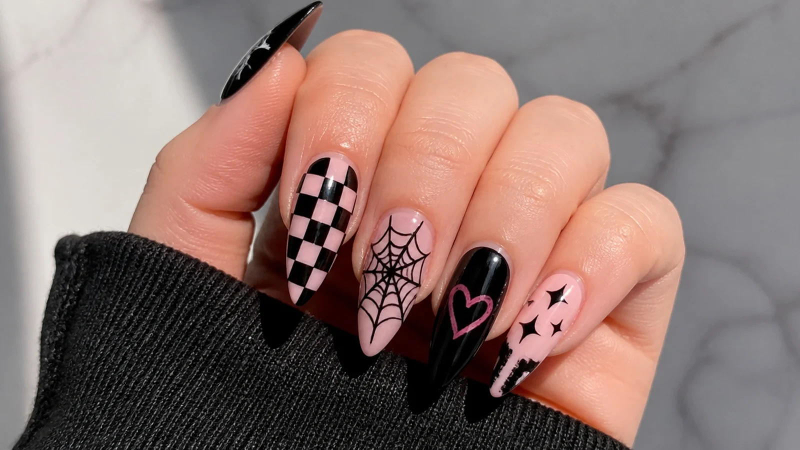 Black emo nails layered with checkerboard, hearts and spiderweb motifs