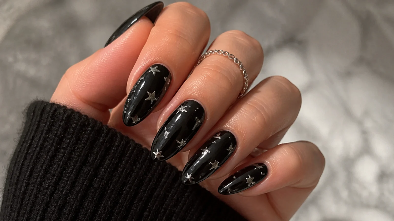 Glossy black emo nails with small silver stars scattered across