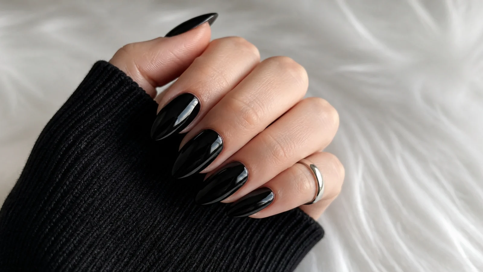 Minimalist glossy solid black emo nails on an almond shape