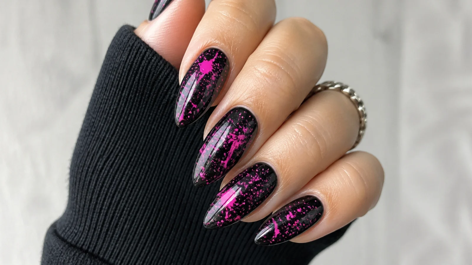 Black emo nails with neon pink paint splatter across the surface