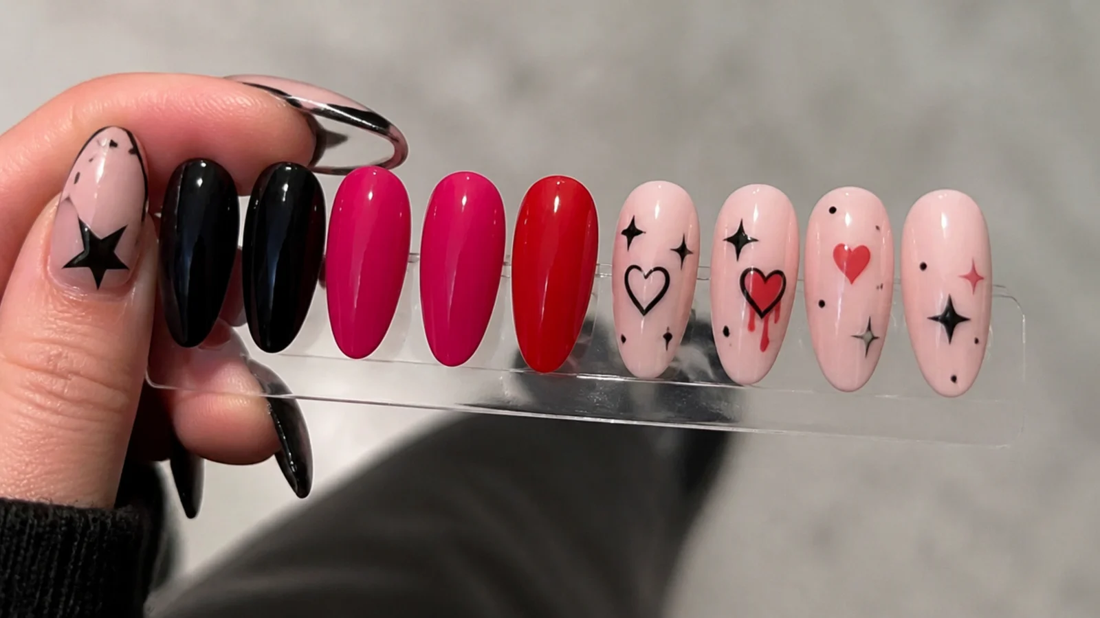 Swatches of black, hot pink and red gel beside emo heart and star motifs
