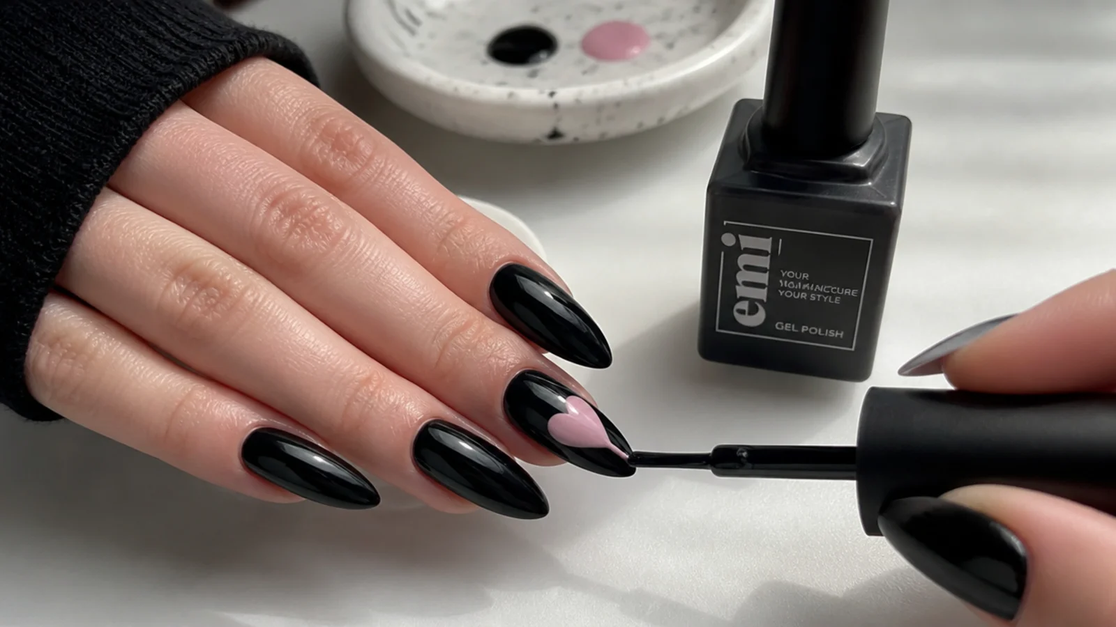 Emo nail supplies with a black base and a heart motif being painted at home