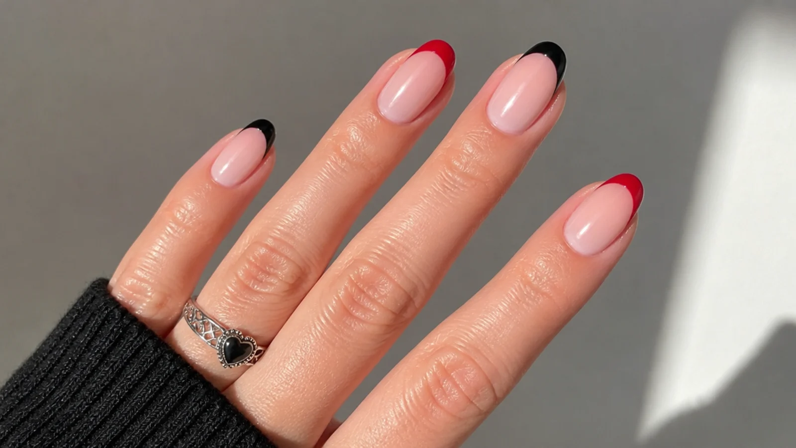 Nude nails with alternating red and black French tips, emo Y2K style