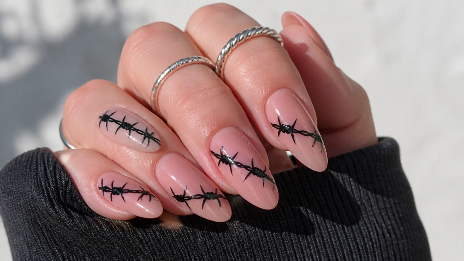 Nude nails with black barbed wire painted across, emo Y2K style
