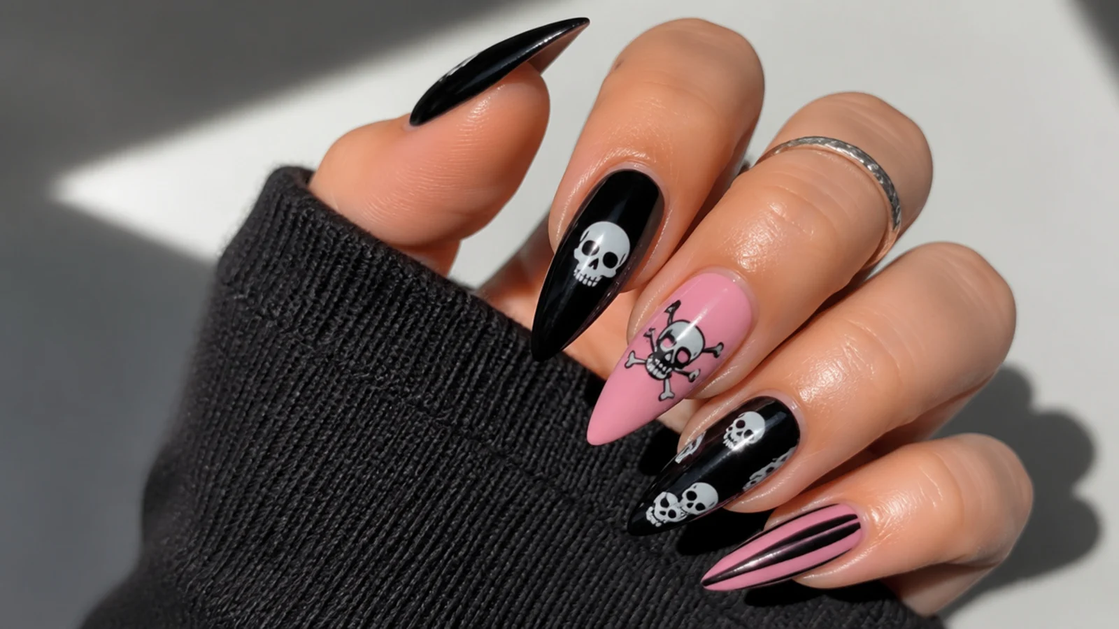 Black and pink nails with small white skull motifs, emo Y2K style