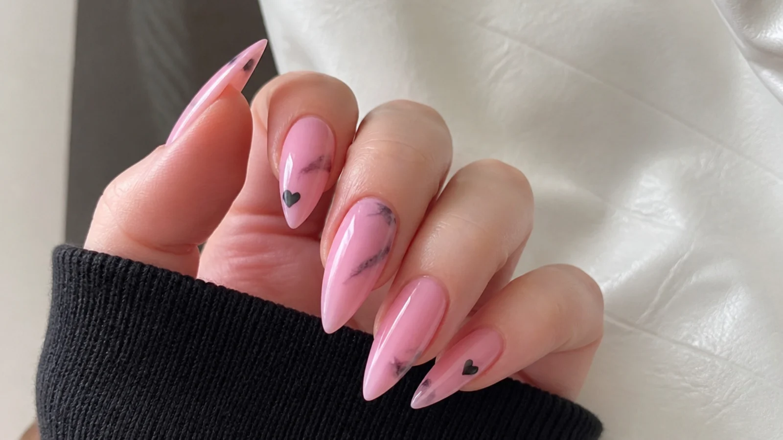Soft pink nails with faint black smudge and tiny heart, emo Y2K style