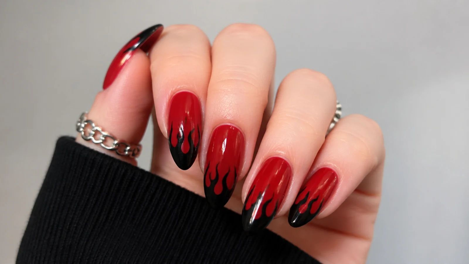 Red nails with black flame licks at the tips, emo Y2K style