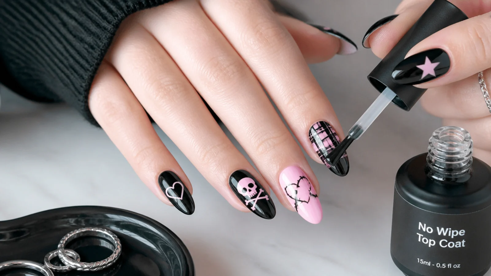 A glossy no-wipe top coat sealing finished black-and-pink emo nails with art