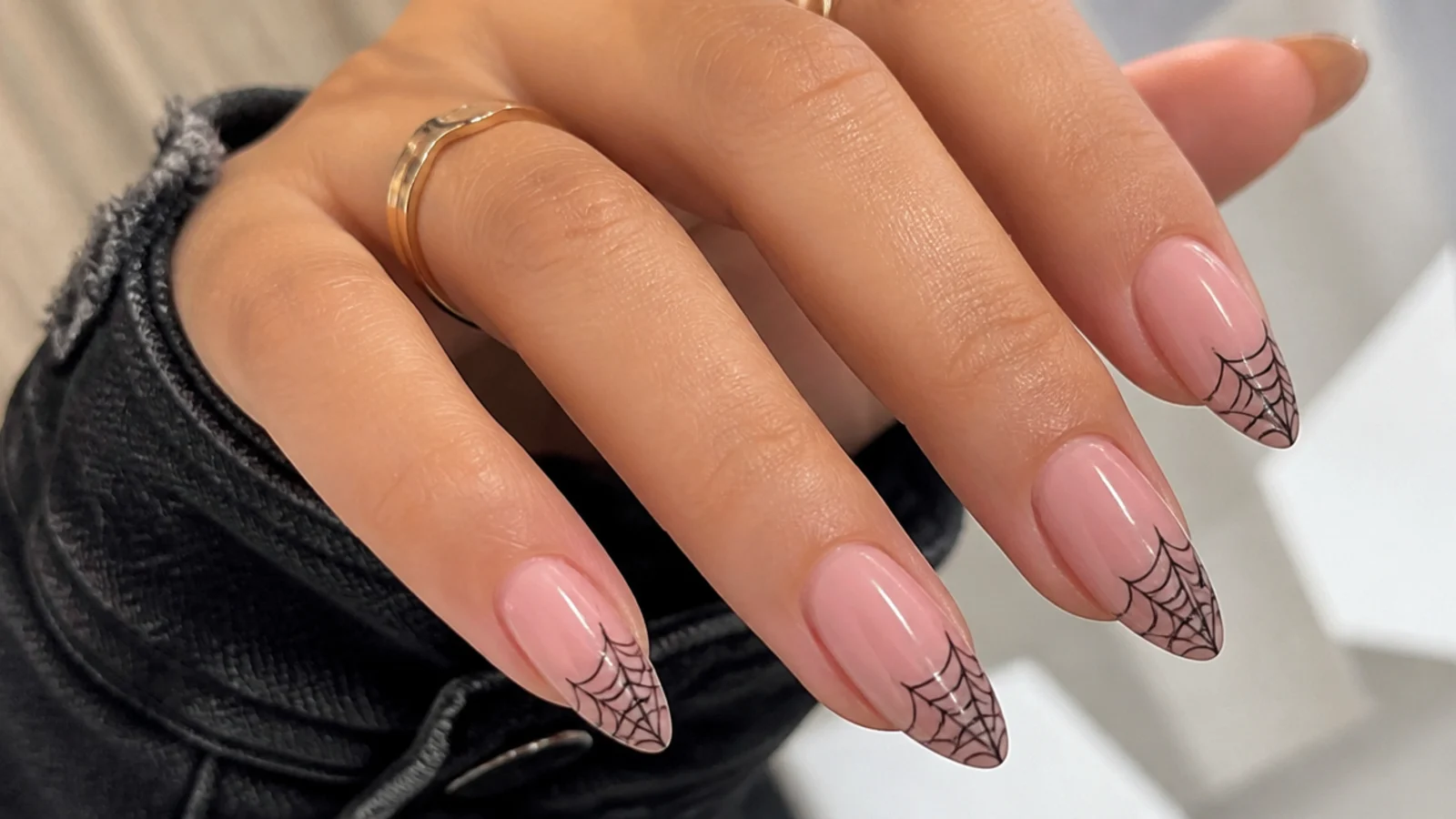 Pale pink emo nails with fine black spiderweb lines in the corner
