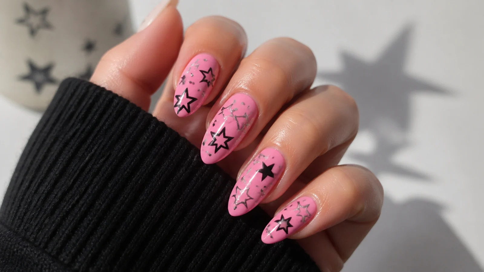 Pink emo nails with black and silver Y2K stars scattered across the nail