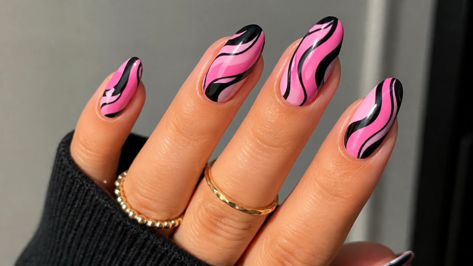 Pink emo nails with retro black swirl waves across the nail
