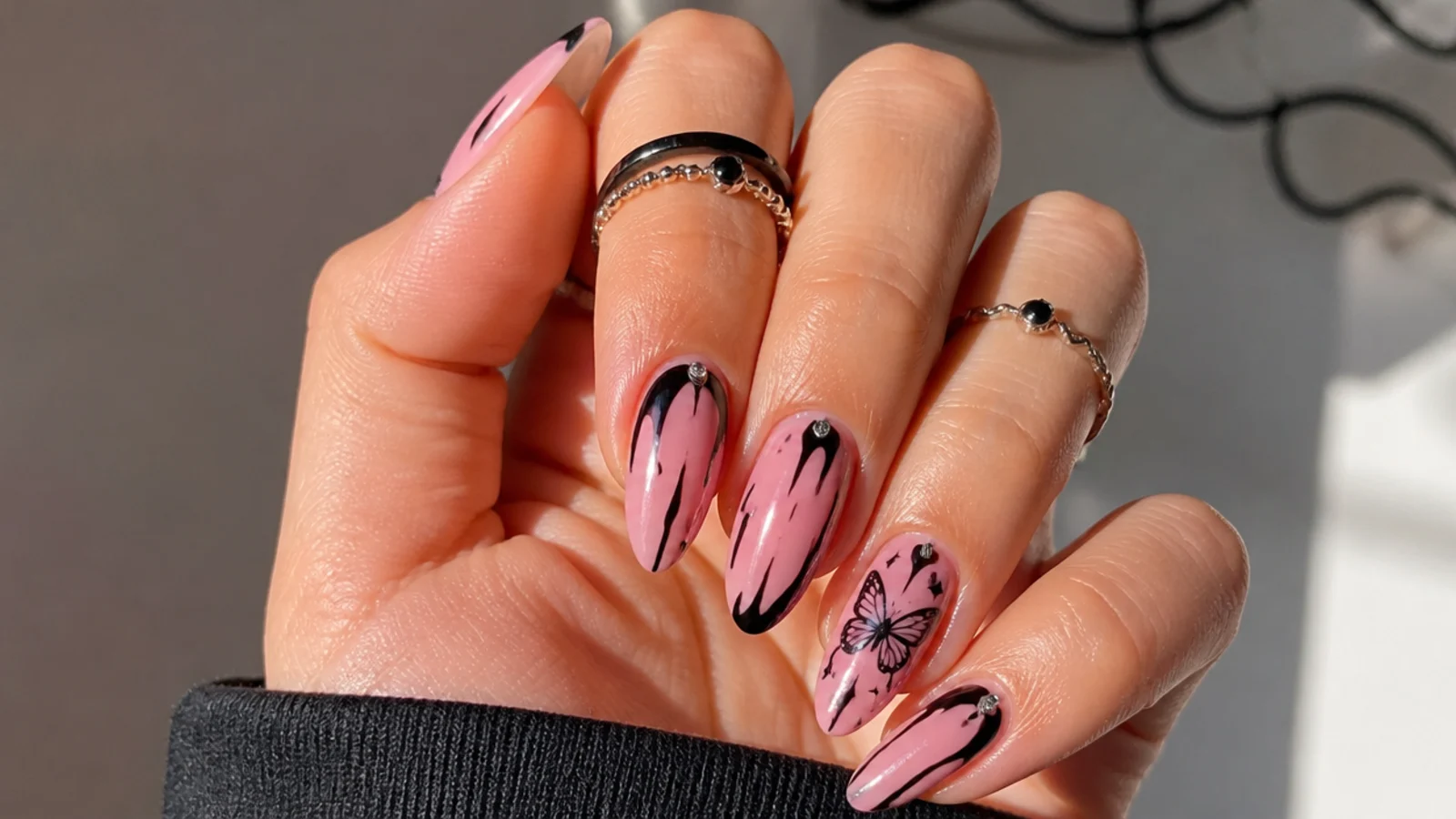 Pink emo nails with a black Y2K butterfly on an accent nail
