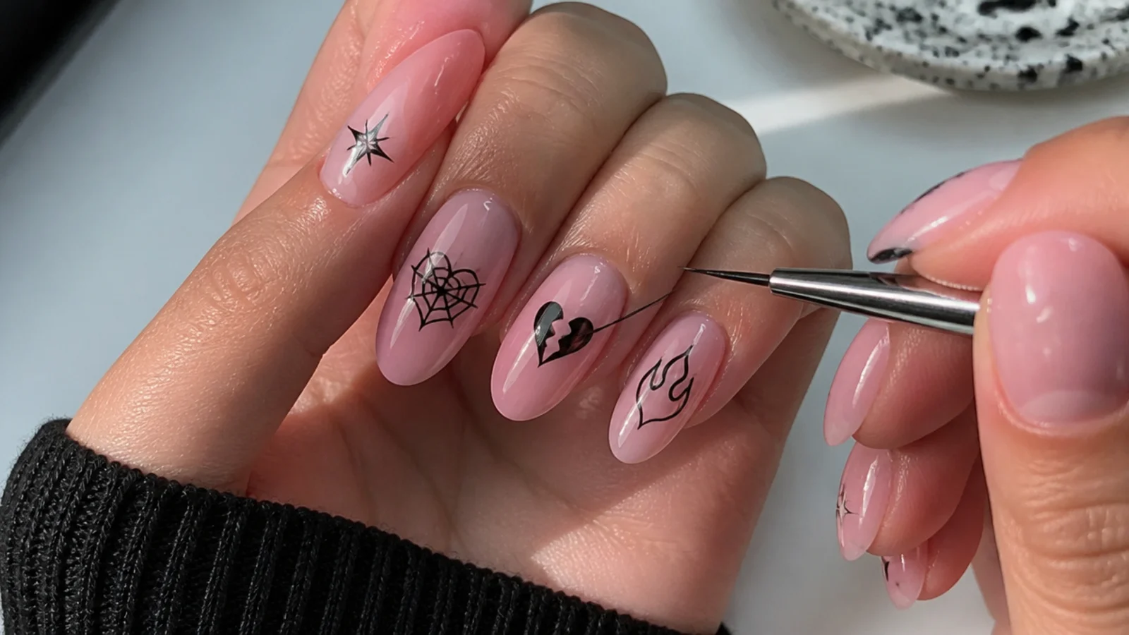Pink gel base with a fine liner brush painting black emo motifs at home
