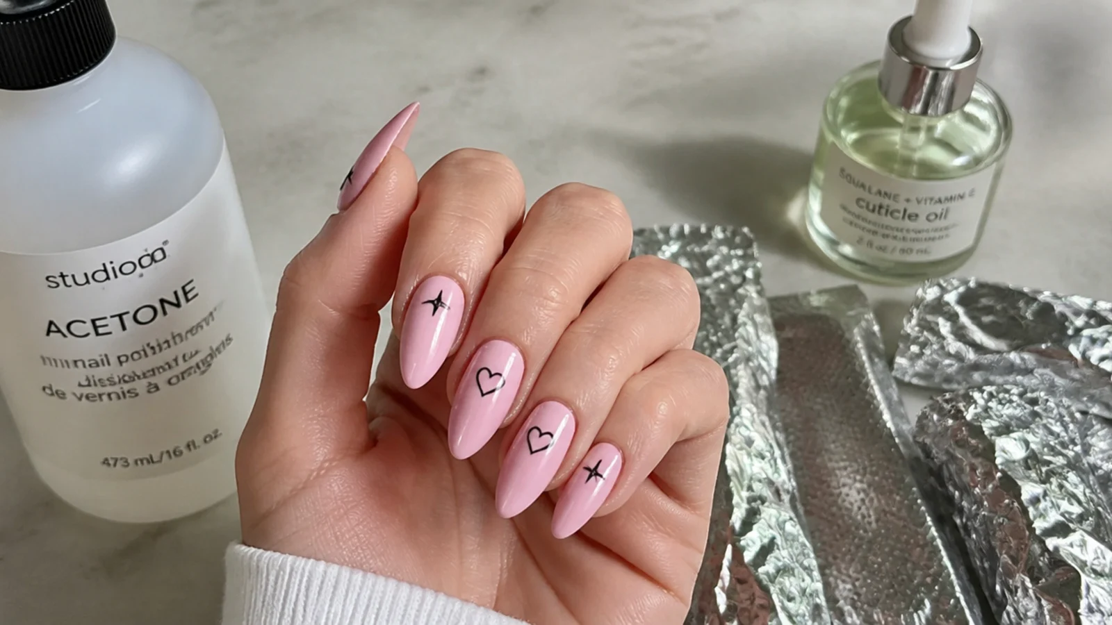 A well-sealed pink emo manicure with cuticle oil beside acetone and foil