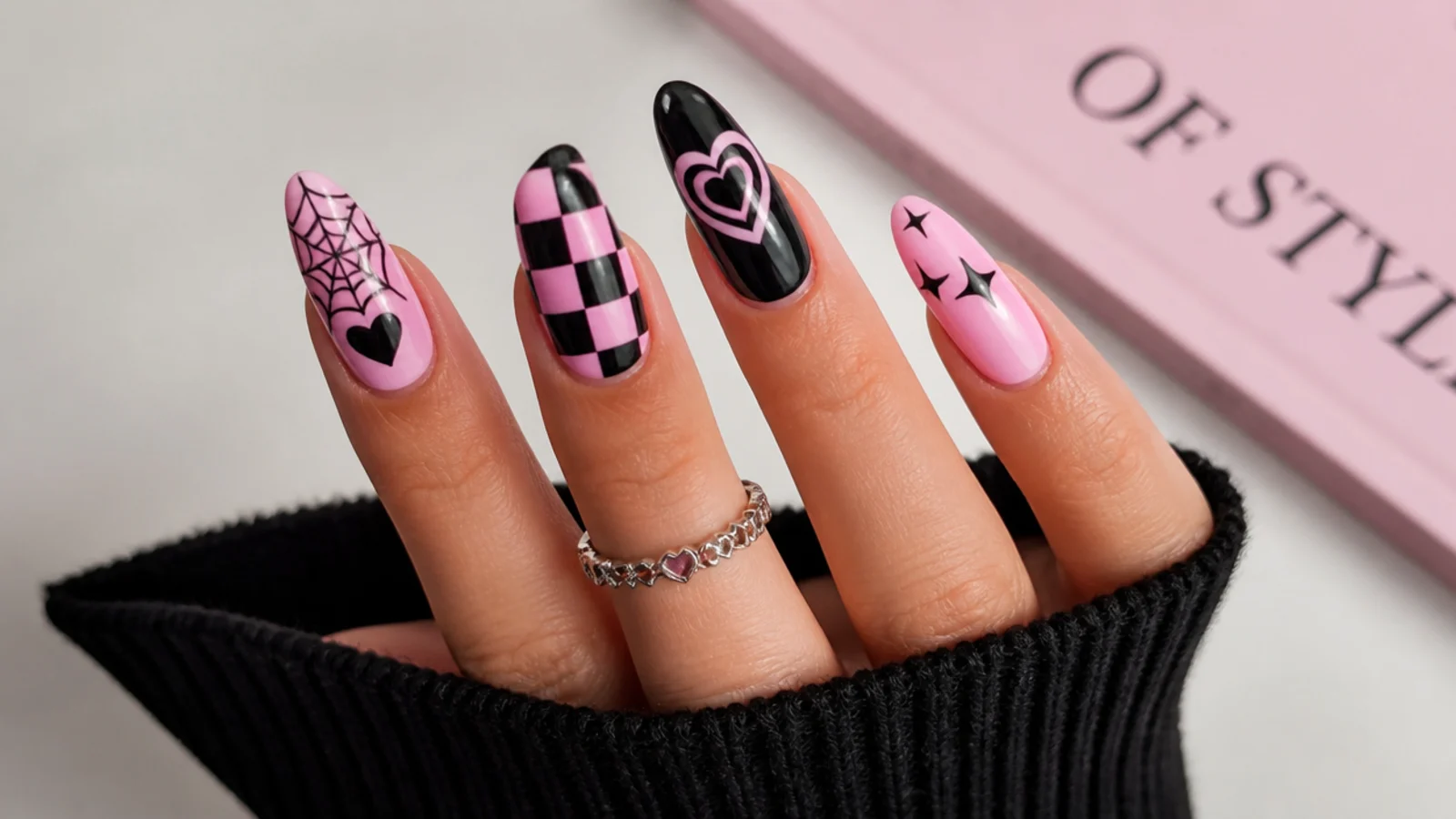 Pink and black emo nails showing checkerboard, hearts and spiderweb motifs