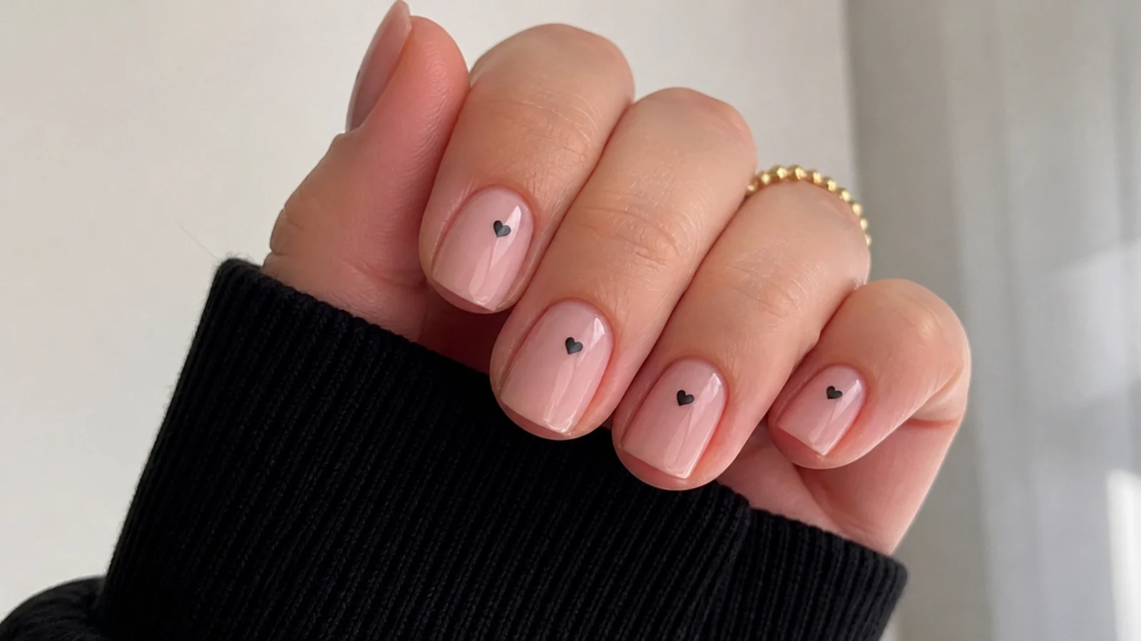 Short round pink emo nails with tiny black hearts for a subtle office look
